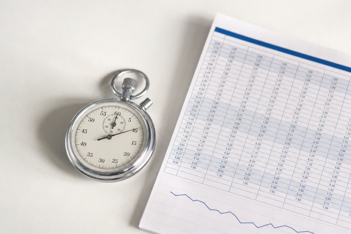 A stopwatch next to a printed spreadsheet with a trend chart